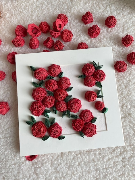 A white square with red roses and green leaves on it.