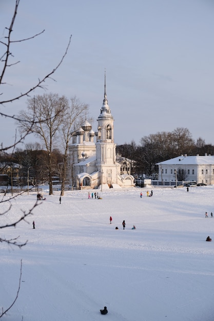 White stone church on the winter embankment on the frozen river