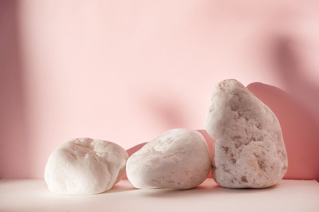 White stones on pink pastel background. Abstract background, mock up minimal scene geometry shape podium for cosmetic product display. Stage pedestal or platform.