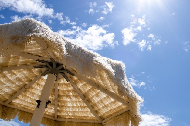 White straw umbrella on the beach against the sky