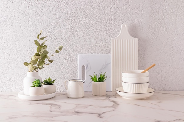 White stylish cutting boards and bowls on the kitchen marble countertop in the interior of the modern kitchen in light colors front view