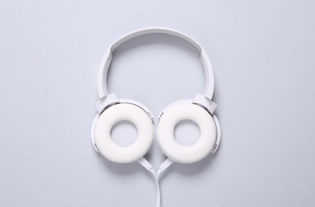 White stylish stereo headphones on gray background Minimalistic music still life music lover Top view Flat lay