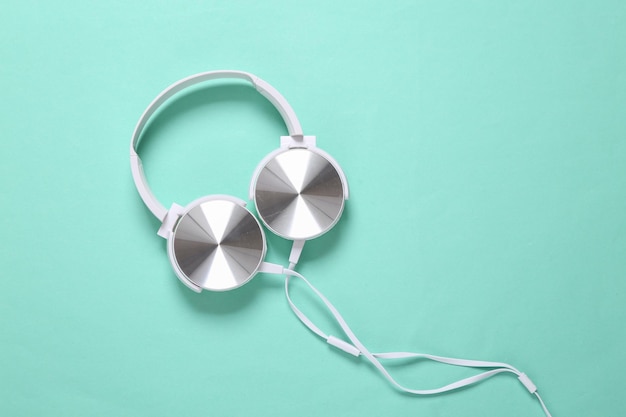 White stylish stereo headphones on mint green background Minimalistic music still life music lover Top view Flat lay