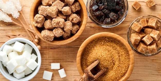 white sugar, cane sugar cubes, caramel in bamboo bowl on dark brown table