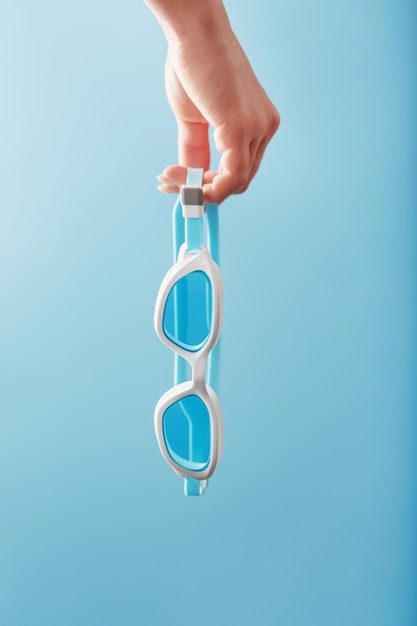 White swimming glasses in hand on a blue background