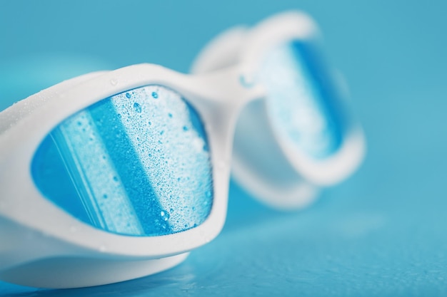 White swimming glasses with a blue lens