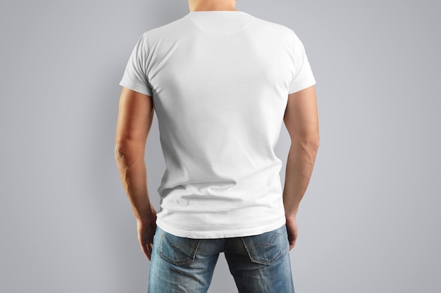 white T-shirt on a young mildew view from the back. isolated on a gray wall.