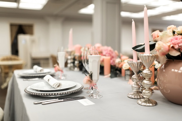 The white table in the restaurant is decorated with fresh flowers. Stylish event decor