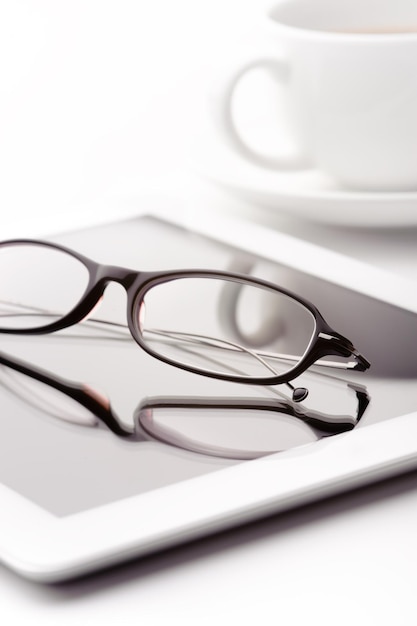 White tablet coffee cup and glasses on a white table