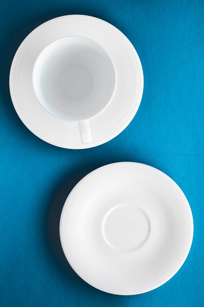 White tableware crockery set empty cup on blue flatlay background