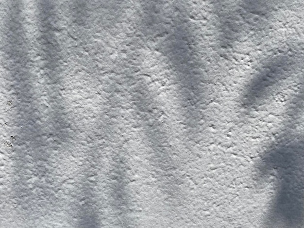 A white textured wall with a pattern of lines and shadows.