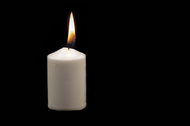 White thick lit candle on black