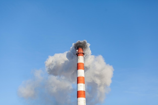 White thick smoke from the boiler room chimney. Smoke against the blue sky. Air pollution.