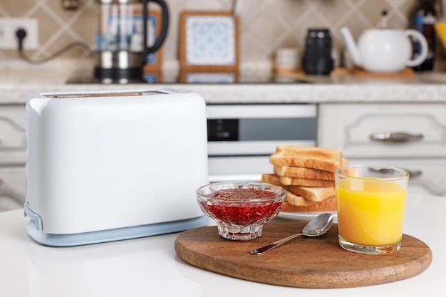 White toaster glass of orange juice slices of toasted bread crispy toasts and raspberry confiture