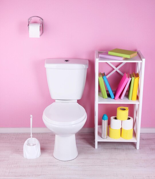 White toilet bowl and stand with books on color wall background