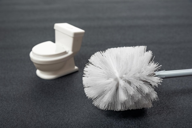 White toilet brush and small toilet bowl on grey background Tools for house cleaning hygiene