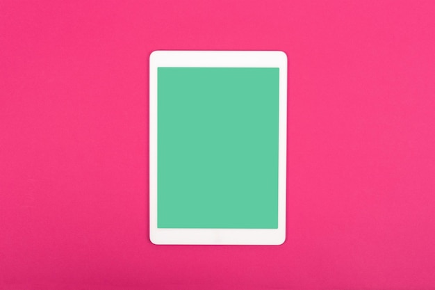 White touchpad with blank green screen on magenta background Flat lay