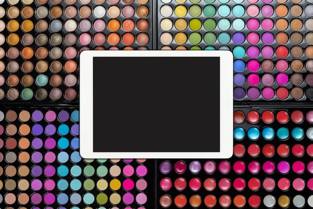 White touchpad with blank screen on colorful eyeshadow palettes eyeshadow makeup palettes with table