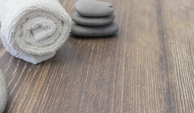 White towel with spa stones on wood