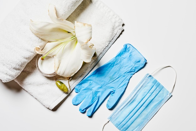 A white towel with a white flower and blue gloves