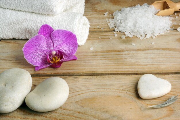 White towels, bath salts and stones for a hot massage on a wooden table