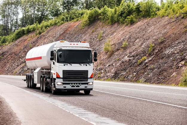 White truck with propane tank moving by a road