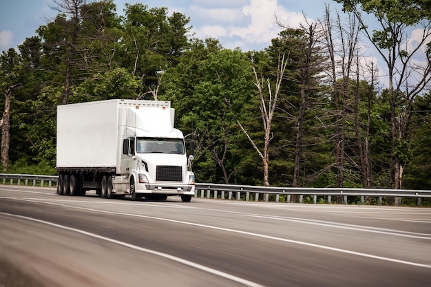 White truck with white conteiner on a road in summer