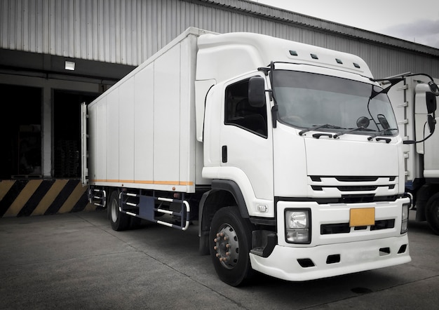 White trucks docking load cargo at distribution warehouse