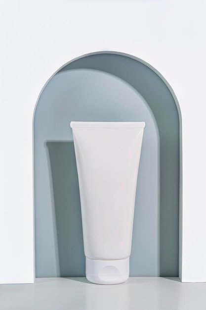 A white tube of cream standing in an arche Cosmetics and beauty mockup