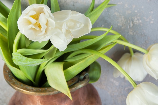 White tulips in old copper vase