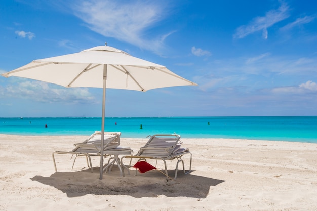 White umbrella and sunbeds at tropical beach