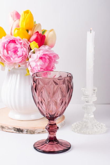 A white vase with flowers and a glass of wine on the table Romantic table setting