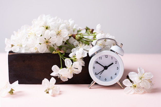 White vintage clock with wooden box with cherry flowers on pink