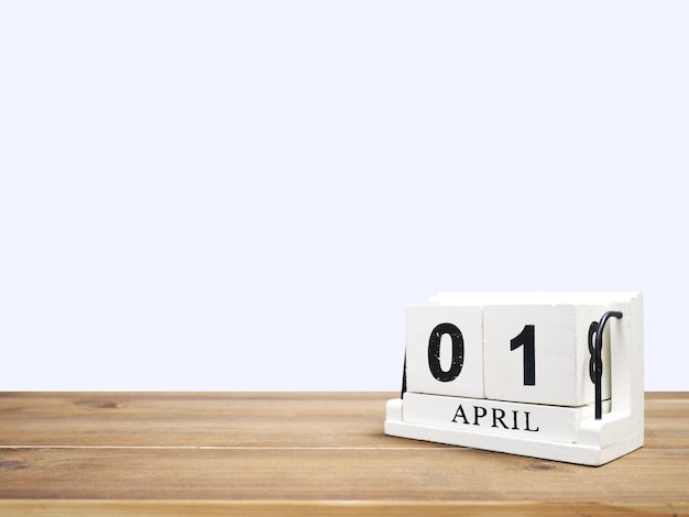 White vintage wood block calendar present date 01 and month April on brown wooden table over grey background with copy space.