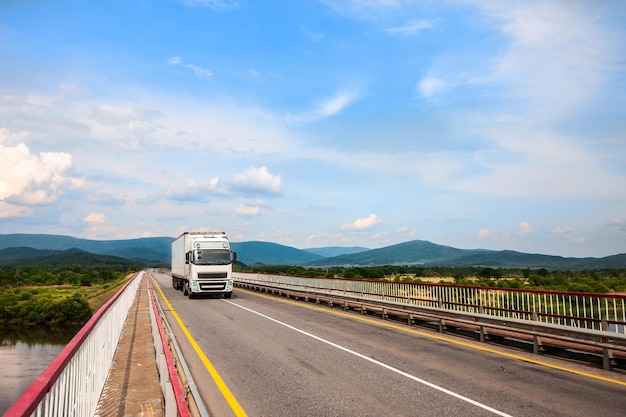 White Volvo truck on a bridge.