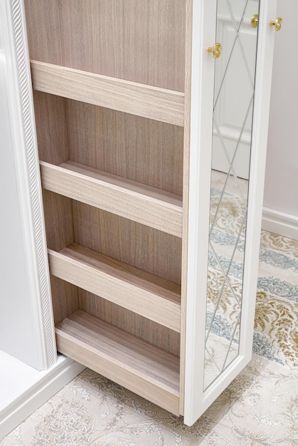 White walk-in closet with mirror facades decorated with rhombus pattern and slide out wooden cabinet