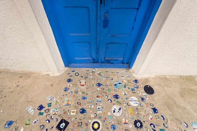 White wall with blue closed wooden door and floor decorated with mosaics