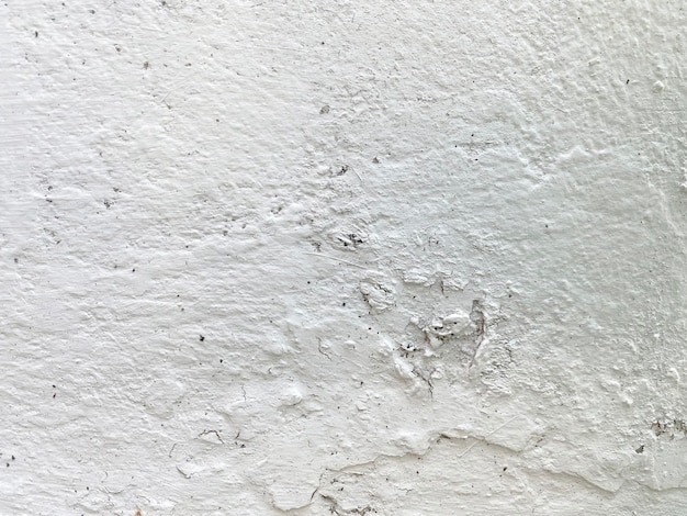 A white wall with a rough textured surface and a black and white paint.