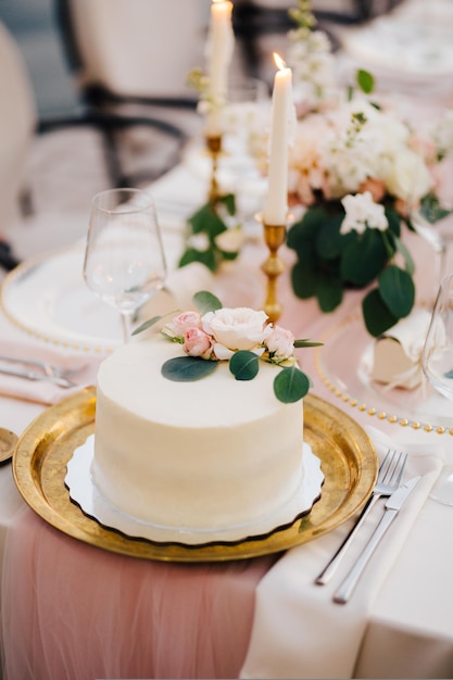 White wedding cake covered with white glaze stands on the table