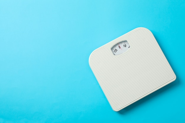 White weigh scales on blue background, top view