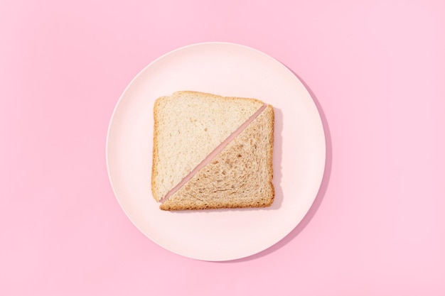 White and whole wheat sandwich slice bread on plate on pink background Flat lay