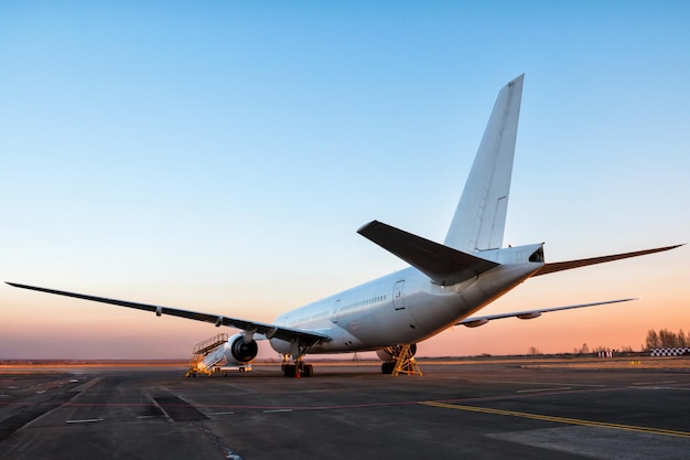 White wide body passenger aircraft at the airport apron in the evening light