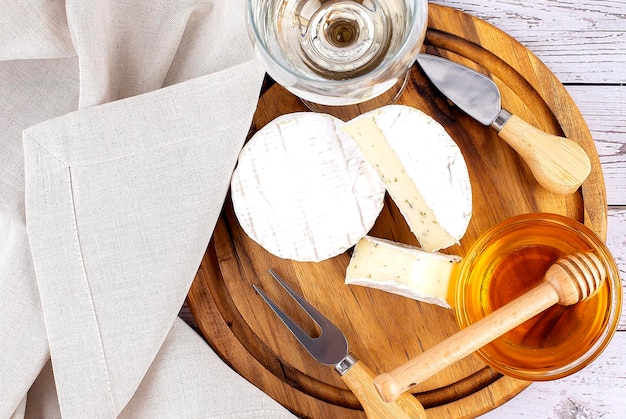 White wine served with camembert cheese honey on wooden board