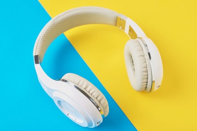 White wireless headphones on a blue and yellow background