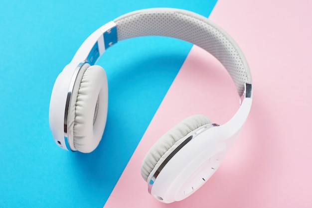 White wireless headphones on a pastel pink and blue background