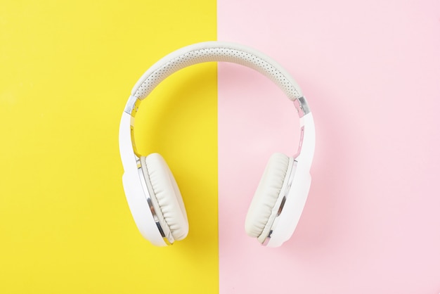 White wireless headphones on a pink and yellow background