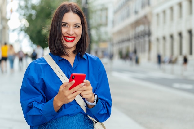 White woman looking at camera while using mobile phone on the street