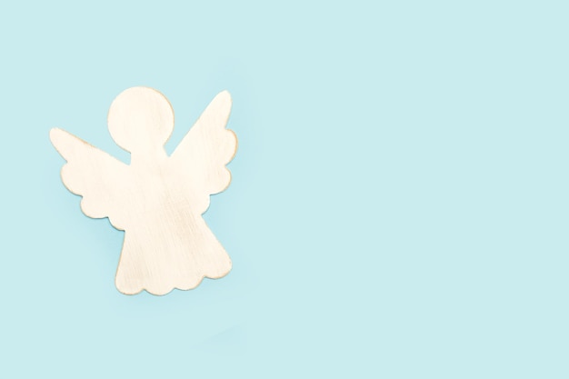 A white wooden angel on a light blue background with copy space