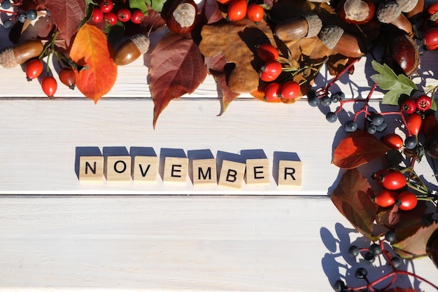 Photo white wooden background with autumn leaves frame and text