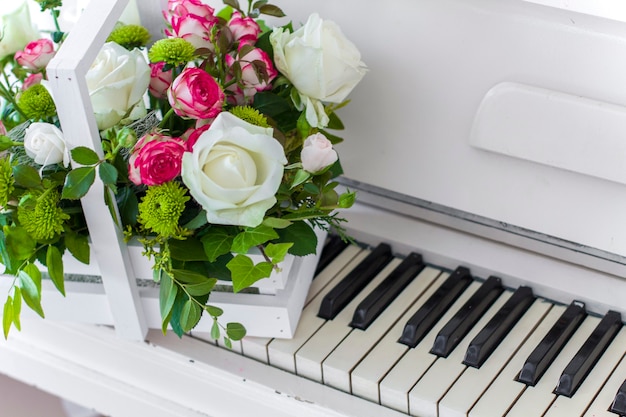 White wooden box with bouquet white and pink roses and chrysanthemums on white piano. Decoration of home. Flowers boxes. Wedding decoration